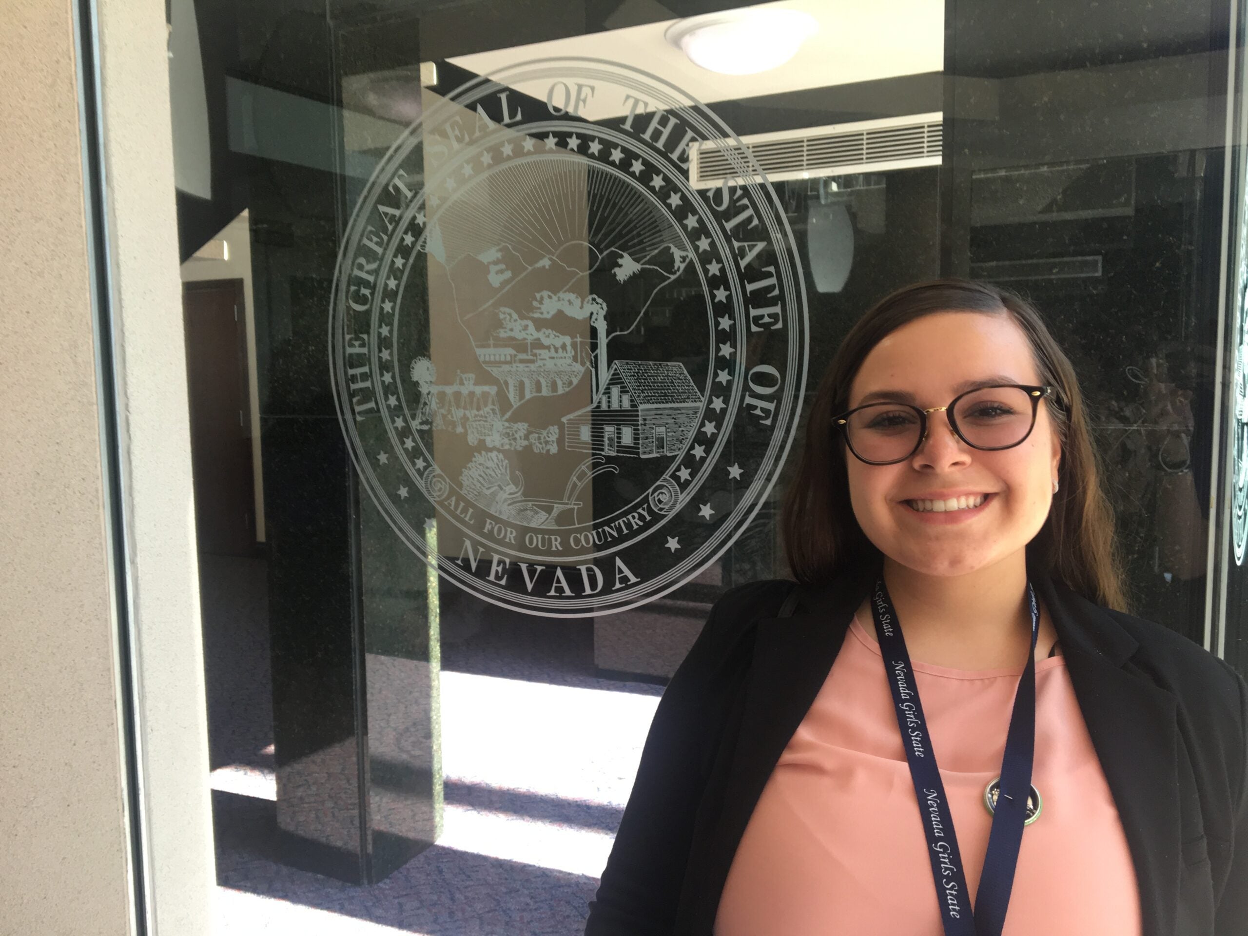 Photo of Esme Vazquez in front of great seal of the state of Nevada